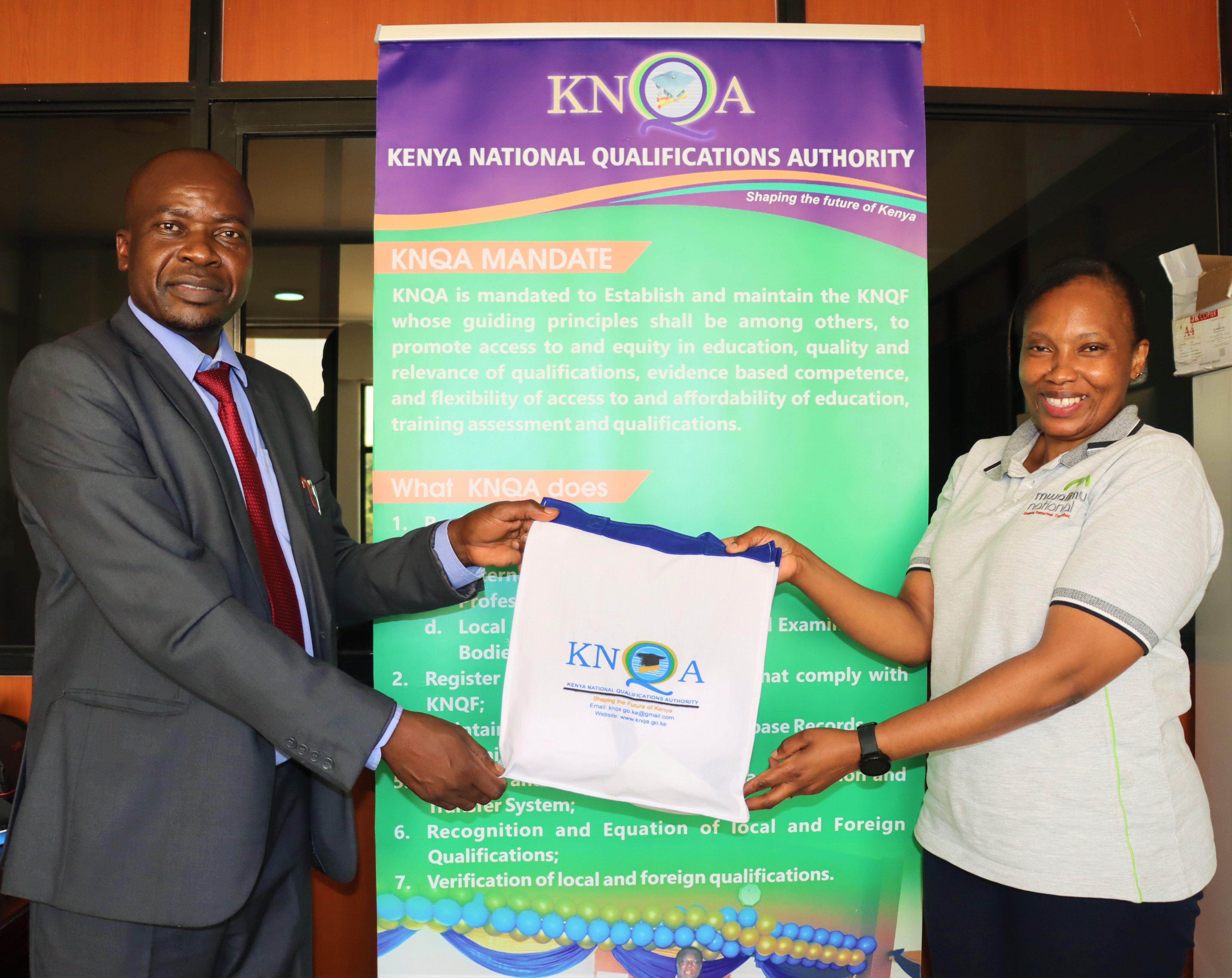 Director Technical Services Mr. Stanley Maindi, brands Ms. Purity Kimathi and Ms. Gladys Mwangi – both branch managers of Mwalimu National Sacco in KNQA regalia during a courtesy call at the Authority’s offices.