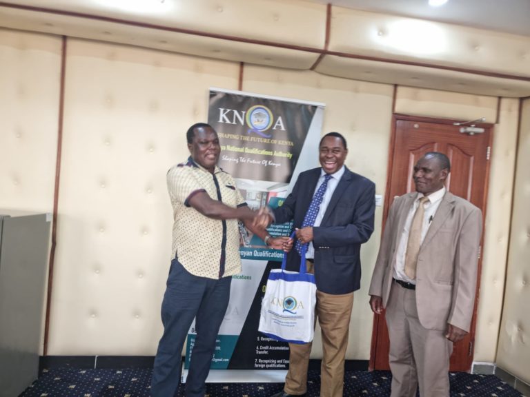 KNQA Director General Dr Juma Mukhwana(l) hands over a gift to Kenya Utalii College  Acting Principal and chief executive officer  Prof Charles Musyoki.Looking on is RAD Deputy Director Mr James Tegeret.